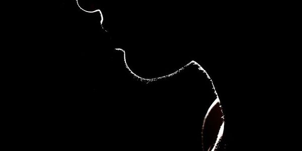 Silhouette of a person in a balance pose against a minimal background.